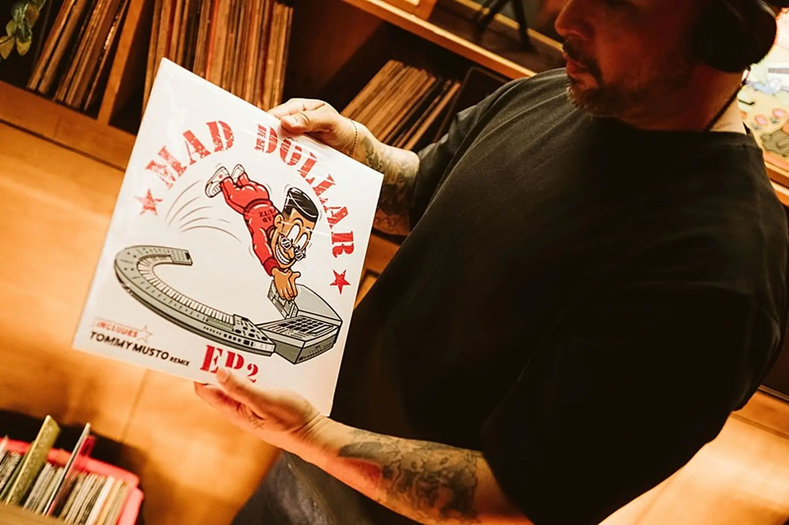 DJ houdt een vinylplaat omhoog voor de platenkast